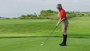 A person is preparing to take a golf shot on a lush green course.