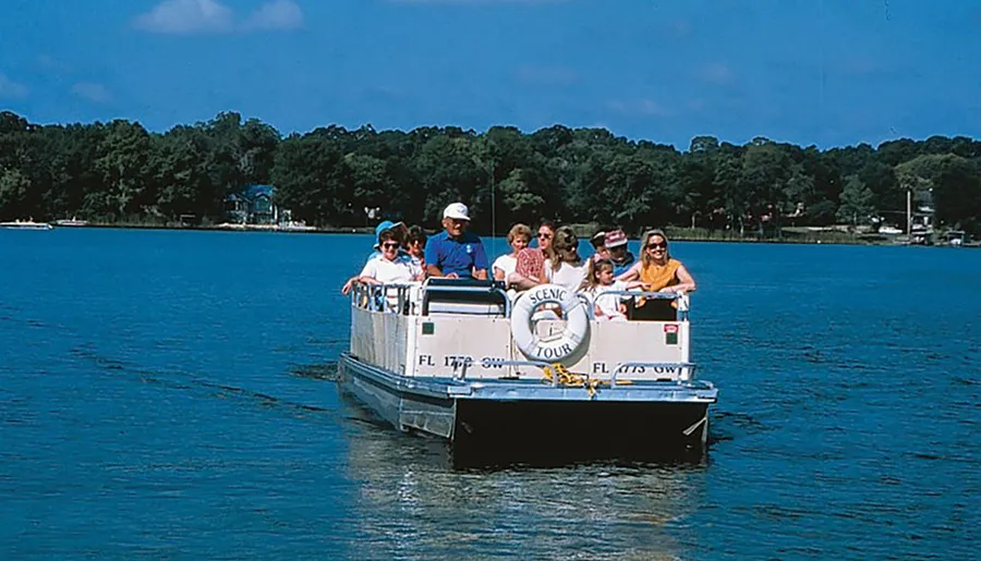 A group of people enjoys a scenic tour on a sunny day aboard a small boat gliding across calm blue waters.