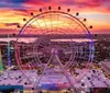 The image showcases a vibrant sunset skyline with a large observation wheel promotional insets for SEA LIFE Orlando Aquarium and Madame Tussauds and people enjoying attractions