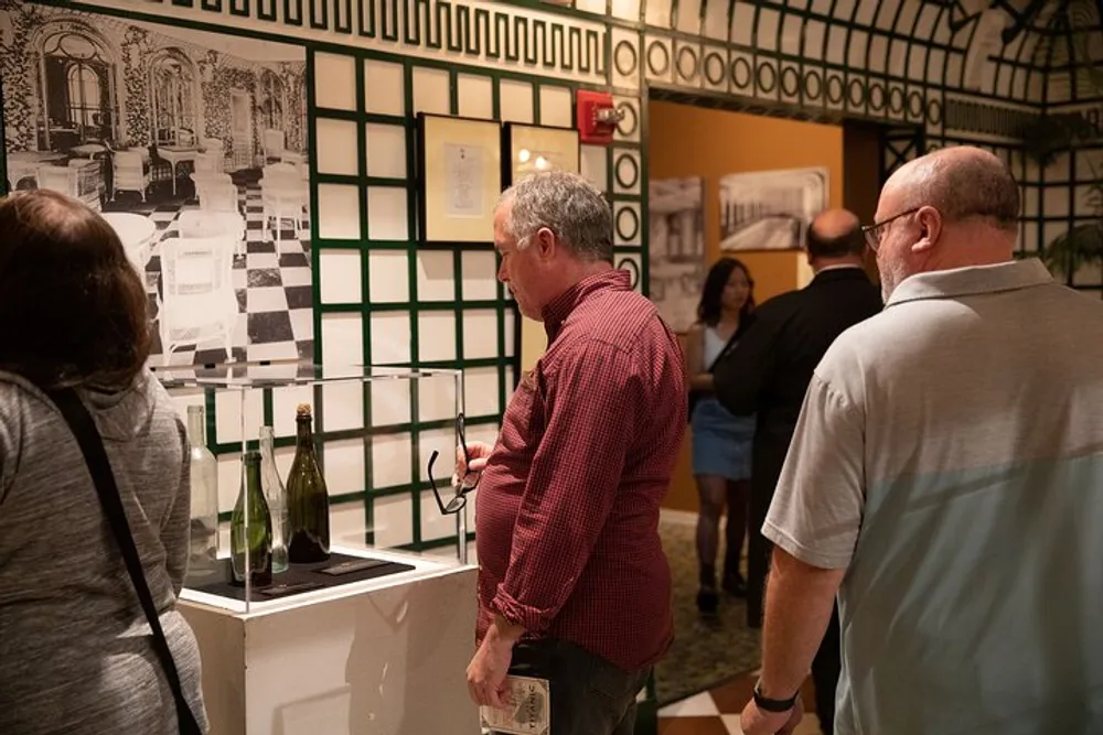 Several people are viewing artworks displayed on the walls during an indoor art exhibition