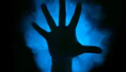 A silhouetted hand is displayed against a blurred blue background, creating a mysterious and eerie atmosphere.