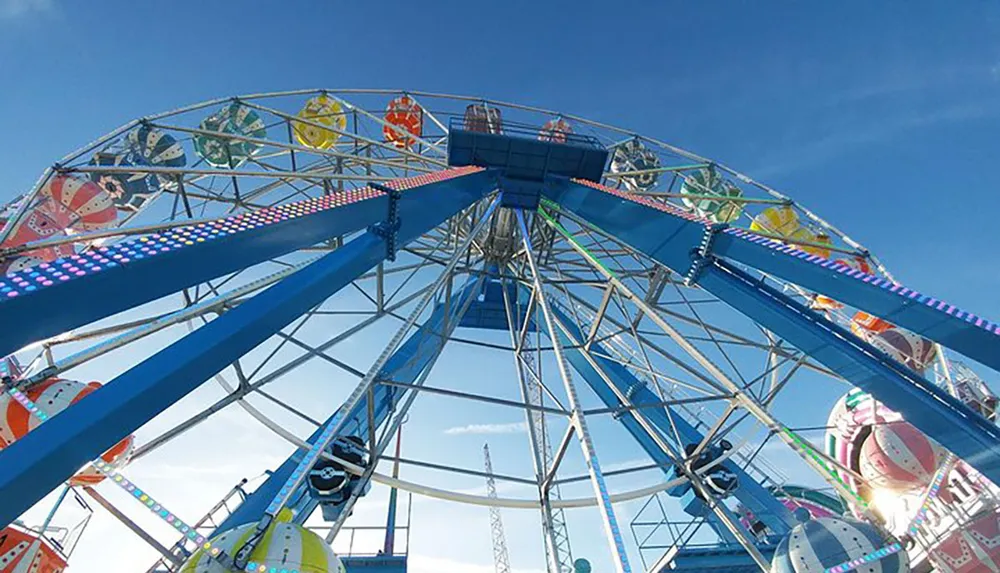 The image captures a vibrant and colorful Ferris wheel against a clear blue sky