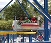 Thrilled riders are descending a steep drop on a wooden roller coaster against a clear sky