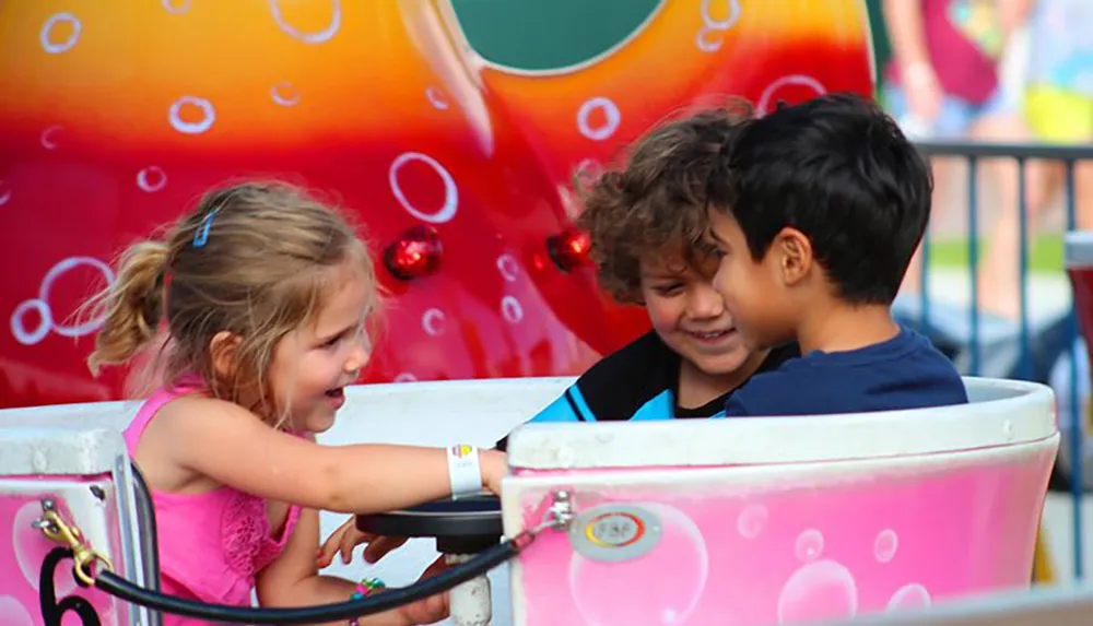 Three children are sharing a joyful moment together on a colorful amusement park ride