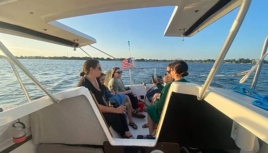 A group of people are enjoying a boat ride on a sunny day with an American flag fluttering in the background.