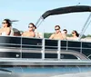 A group of people is enjoying a boat ride on a sunny day with some sitting at the back and one person taking a selfie in the foreground