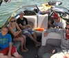 A group of people is enjoying a boat ride on a sunny day with some sitting at the back and one person taking a selfie in the foreground