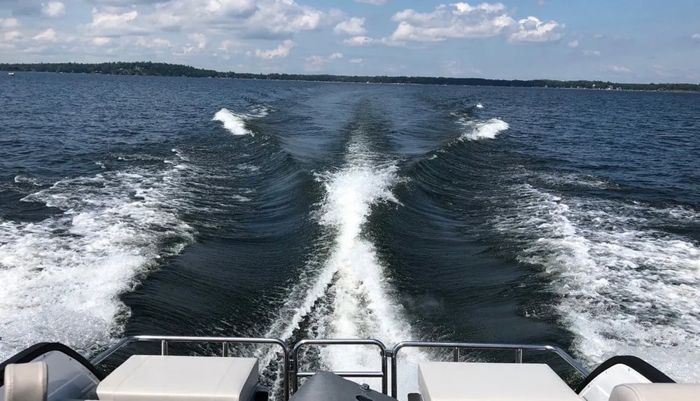 A boat is moving through water generating a V-shaped wake as seen from the stern