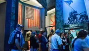 Visitors are observing exhibits, including an American flag and wartime imagery, at a museum.