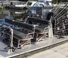 The image shows a large airboat with a metal protective cage over its propeller docked at a pier with other boats in the background
