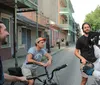 A group of men are engaged in a conversation on a street with colorful buildings two of whom are on bicycles