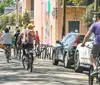 A group of cyclists and a pedicab are sharing a sunny tree-lined street with parked cars illustrating an urban bike-friendly environment