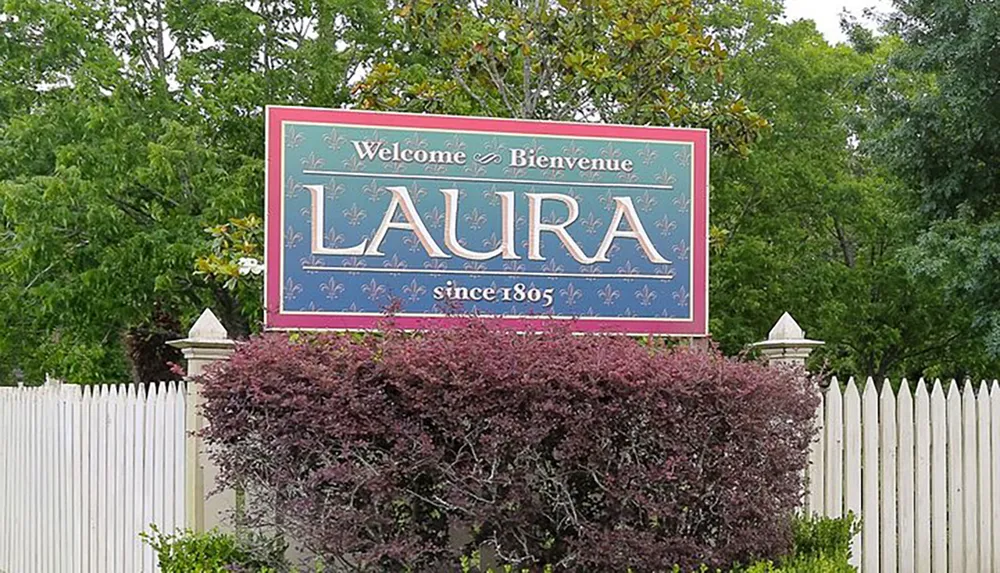 The image shows a welcoming sign for Laura with the text Welcome  Bienvenue above and since 1805 below indicating a historical significance or establishment date for the place named Laura