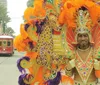 A joyful person is posing with a bright smile in front of elaborate carnival costumes