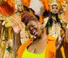 A joyful person is posing with a bright smile in front of elaborate carnival costumes