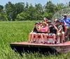 A group of people are taking a ride through a grassy wetland on an airboat