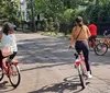 Two people are riding bicycles through a scenic park with large trees draped in Spanish moss