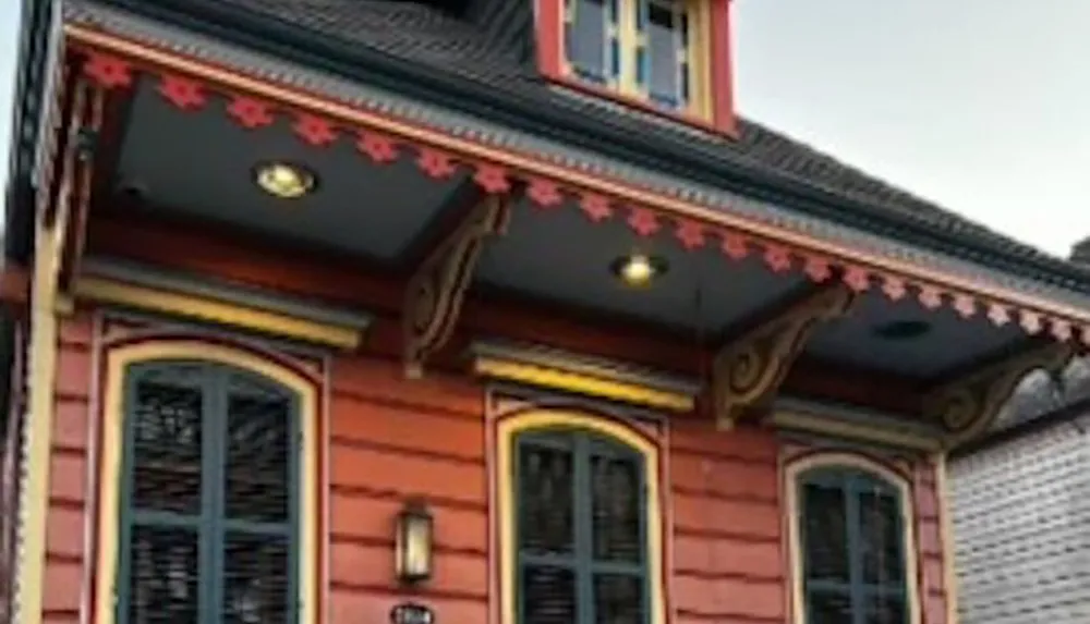 This image shows the intricately detailed facade of a building with decorative woodwork and a distinct orange-red color