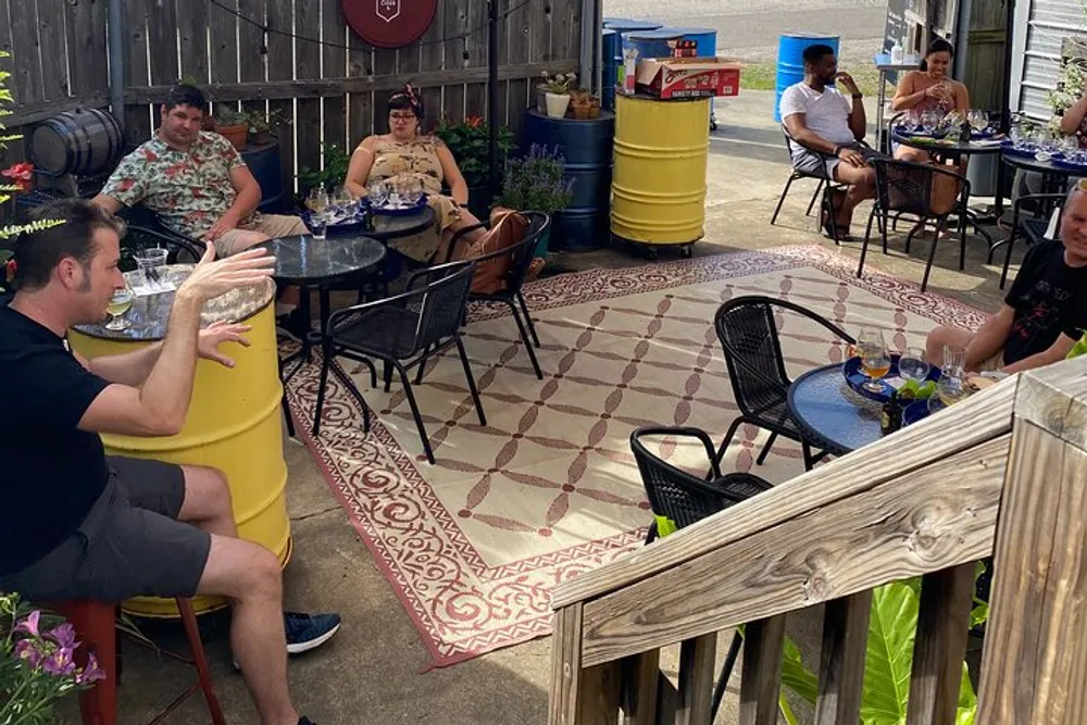 People are relaxing and enjoying drinks at an outdoor patio area with casual seating arrangements