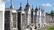 The image shows a row of above-ground tombs and mausoleums with varying designs, characteristic of a historic cemetery.