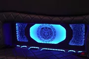 The image shows a car's luxury interior featuring blue ambient lighting and a Versace logo illuminated on the partition.