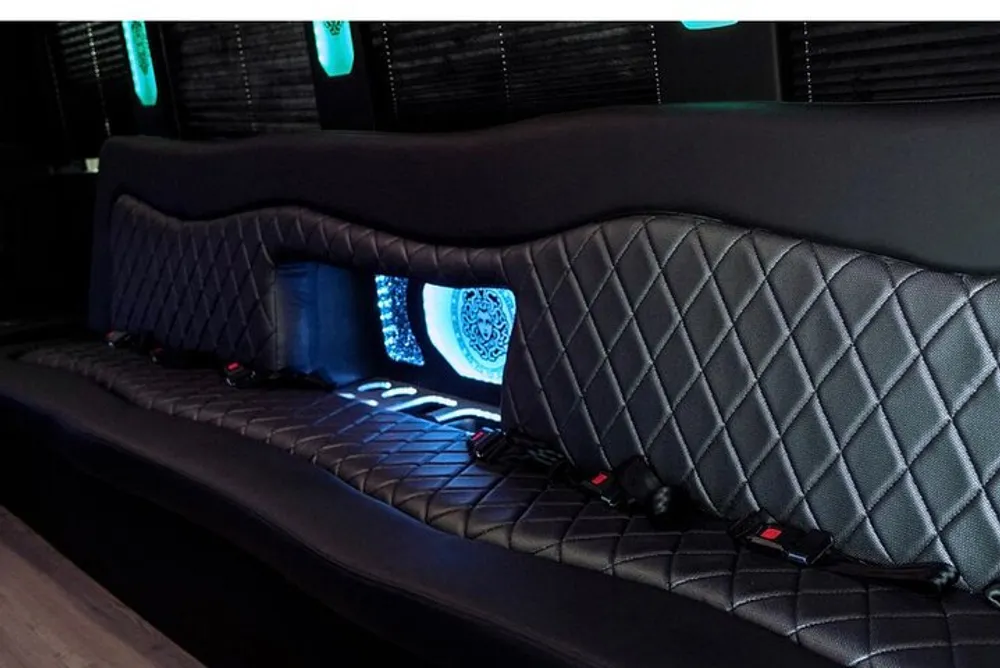 The image shows an interior view of a luxury vehicle with a quilted leather bench seat ambient lighting and stylized elements likely a limousine or customized van