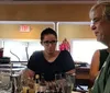 A group of people is posing with smiles behind a bar counter cluttered with cocktail-making equipment and glasses