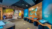 The image shows a modern museum exhibit with interactive displays, colorful informational panels, and a map highlighting Southern Jewish communities.