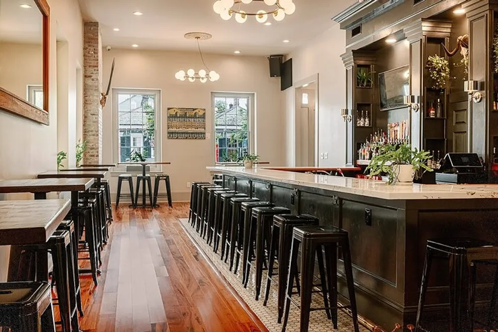 The image shows a well-lit stylish interior of a bar with a long counter high stools and dining tables featuring a mix of modern and rustic elements