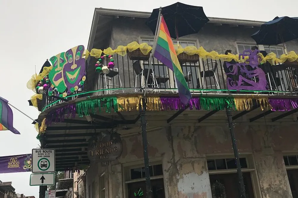 A balcony is festively decorated with Mardi Gras colors and a pride flag suggesting a celebration of cultural and LGBTQ pride