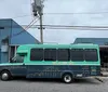 A colorful mural with vibrant mythical creatures adorns a building behind a teal-colored bus on a wet street