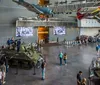 A group of people explore a museum exhibit featuring historical photographs and interactive displays in a dimly lit arched room