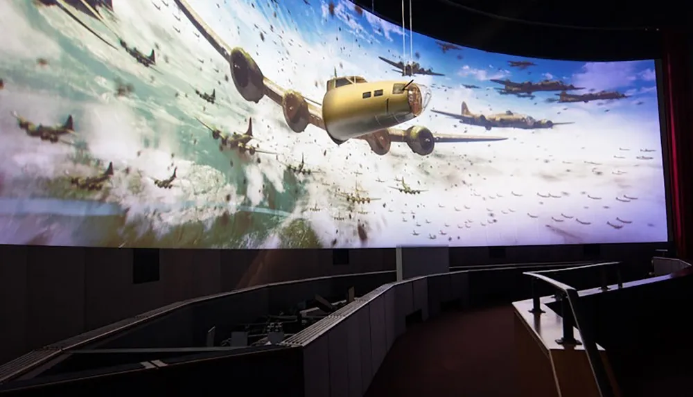 The image shows a large immersive screen projection of vintage military airplanes flying in formation over a vast landscape viewed from the interior of a theater or exhibition space