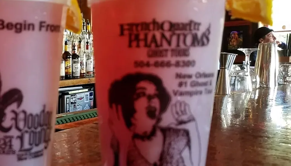 The image shows a bar counter with two novelty cups from the Voodoo Lounge advertising the French Quarter Phantoms Ghost Tours