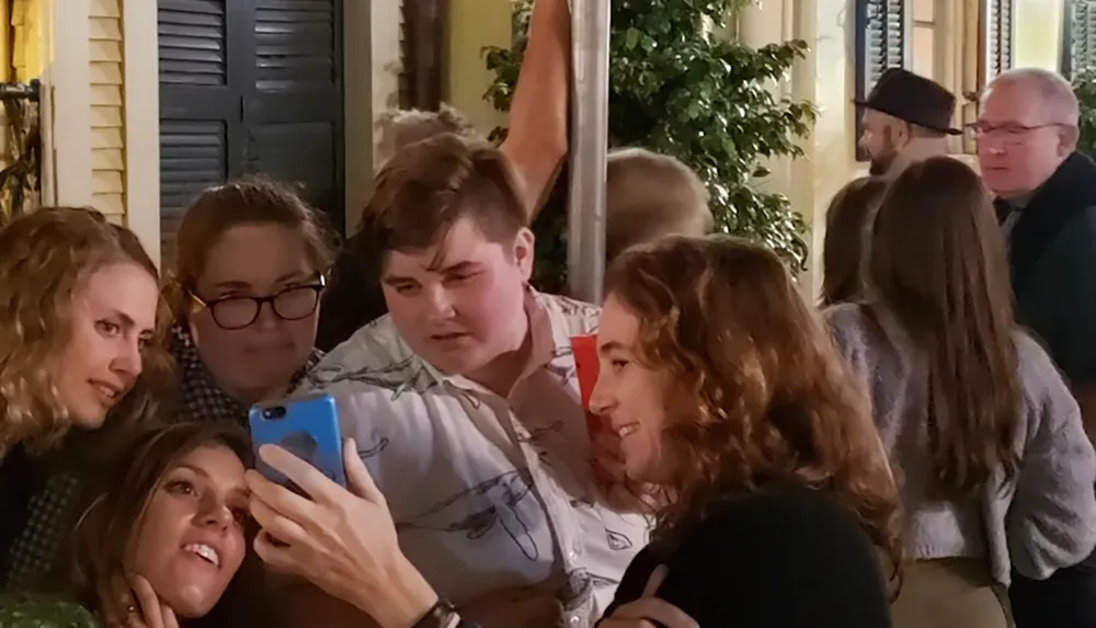 A group of people are gathered closely taking a selfie with a smartphone