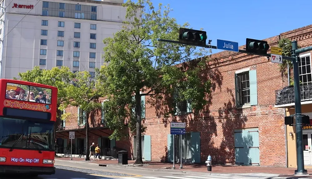 The image shows a CitySightseeing tour bus driving past a brick building on Julia Street in an urban area with a Marriott hotel in the background