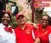 Three people in uniform are smiling in front of a Stop 5 sign