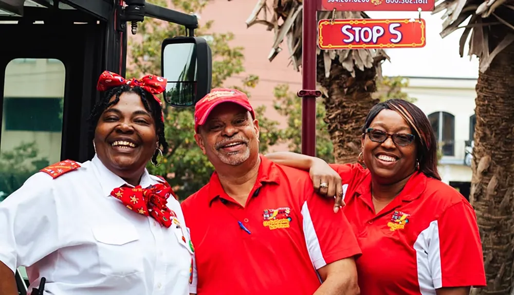 Three people in uniform are smiling in front of a Stop 5 sign