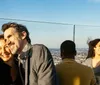 A group of people enjoys a sunny day on a rooftop with a panoramic city view