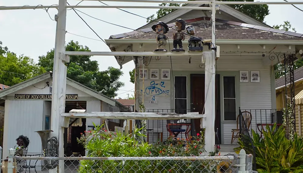 The image shows a small house with quirky decorations on the porch labeled Spirit of New Orleans Museum surrounded by greenery