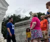 A group of people is gathered near a mausoleum in a cemetery