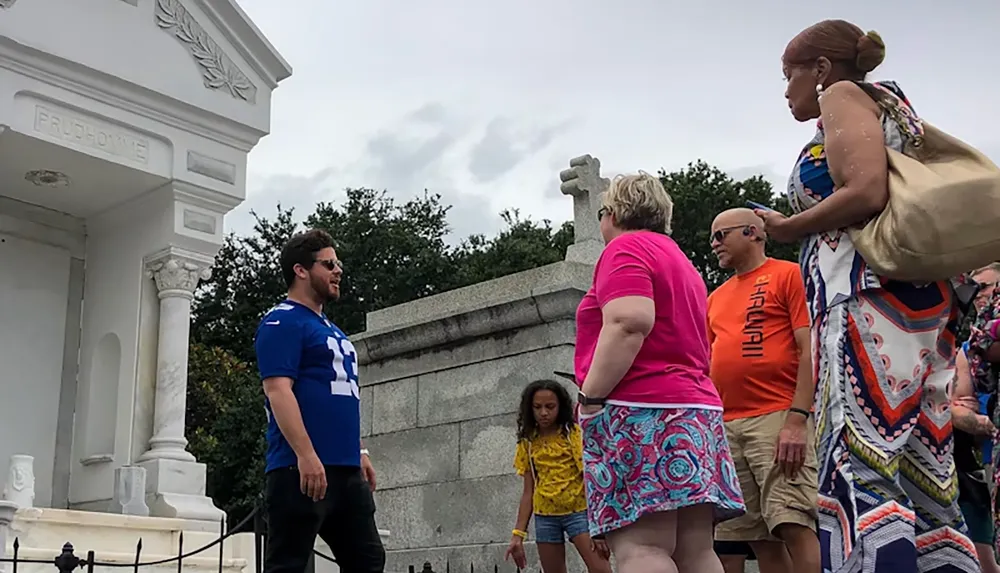 A group of people is gathered near a mausoleum in a cemetery