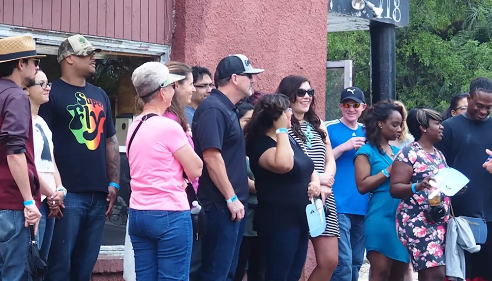 A group of people is standing together outside a building appearing to enjoy a social gathering