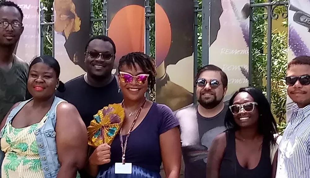 A group of people smiling and posing outdoors in front of decorative posters