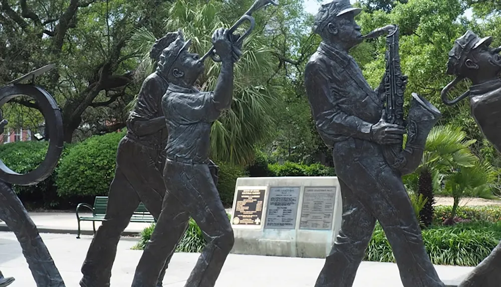 The image depicts bronze statues of jazz musicians playing instruments in a park setting