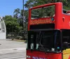 A group of people are walking by a red double-decker CitySightseeing bus with a Hop-On Hop-Off sign