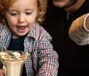 A joyful child eagerly reaches for a dessert with a spoon