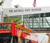 A red sightseeing bus is parked in front of The National WWII Museum