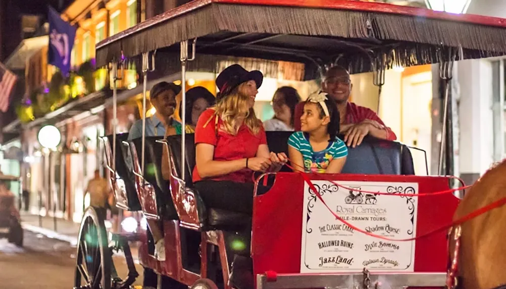 A group of people are enjoying a horse-drawn carriage ride on a lively city street at night