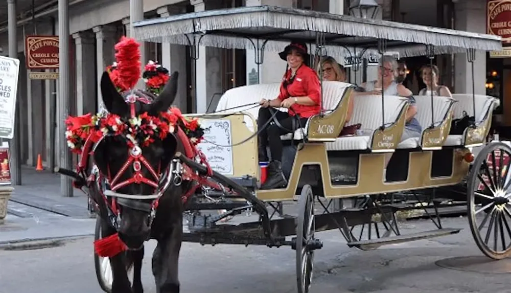 A horse-drawn carriage decorated with red flowers carries passengers through a city street